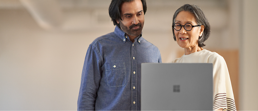 Two colleagues collaborating over a laptop in an office environment.