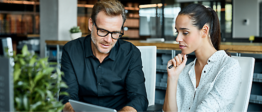 A men in black shirt and a women in white shirt looking at a tablet