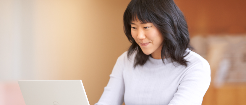 Woman working on a laptop with focused attention.