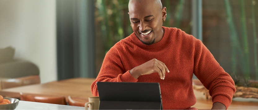 Um homem está sentado em uma mesa com um laptop.