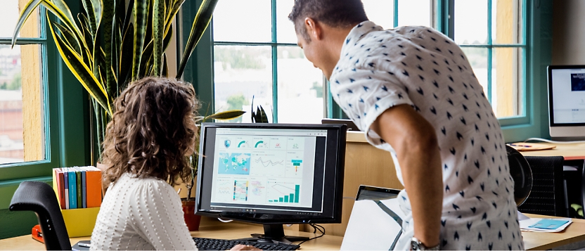 A man and woman looking at a computer screen.