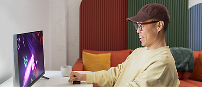 A man sitting in front of a monitor playing video games.