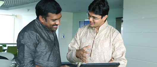 A couple of men looking at a computer and smiling