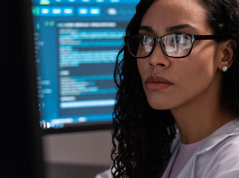 A person wearing glasses and a white lab coat