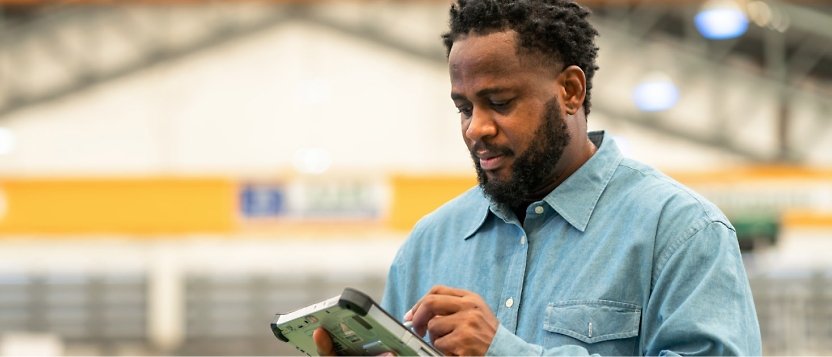 A man is using a tablet in a warehouse.