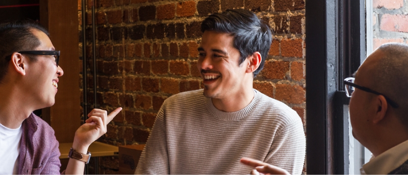 A group of men sitting around a table talking.