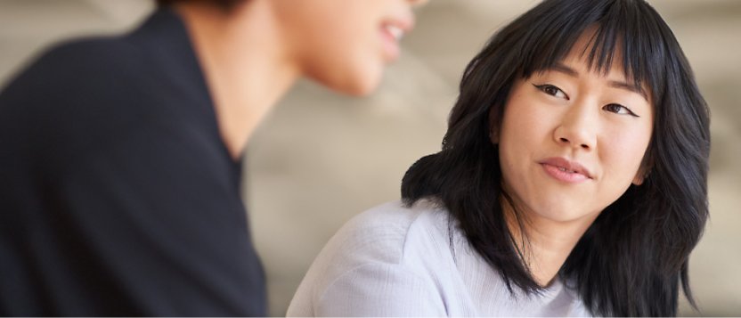 A woman and man talking to each other, the man's face is shown in blur