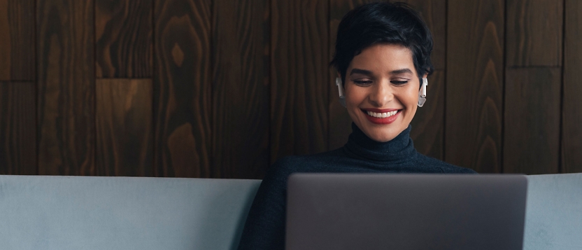 Een vrouw die op een sofa zit en op haar laptop werkt