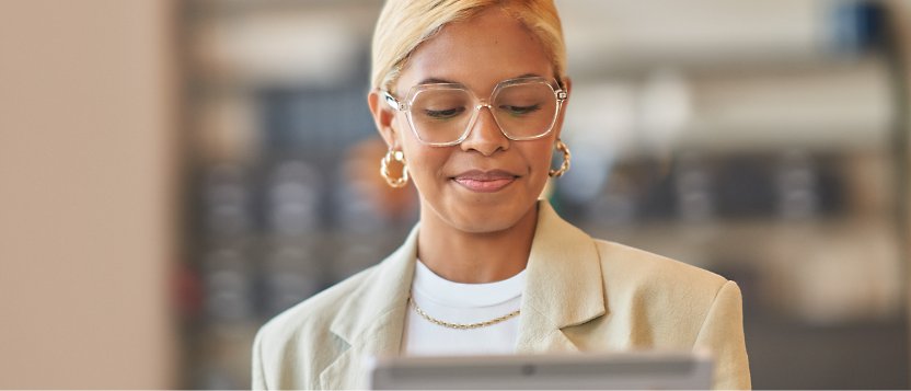 Uma mulher a usar óculos a sorrir e a olhar para um tablet