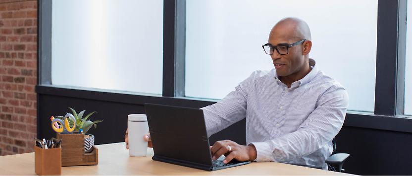 A person sitting in office in desk and using his laptop