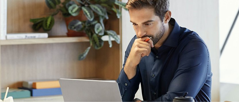 A person using his laptop with his one hand placed on his chin