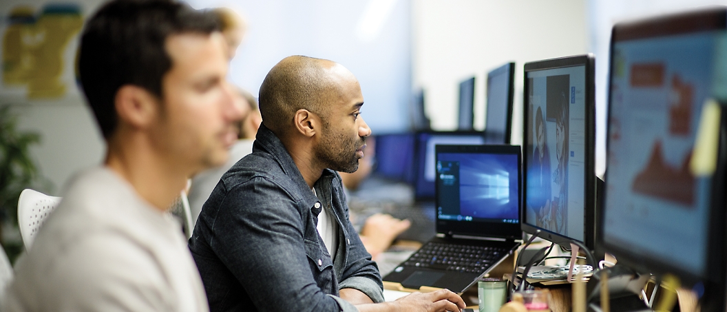 Een groep personen die op computers werken in een kantoor.