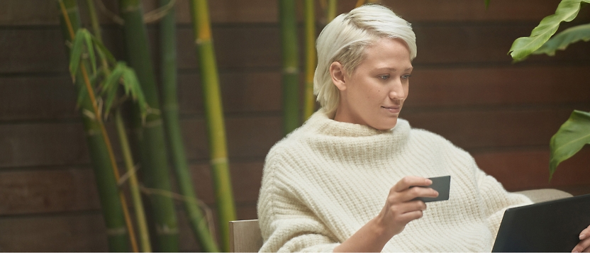 A woman sitting on a couch with a laptop and a credit card.