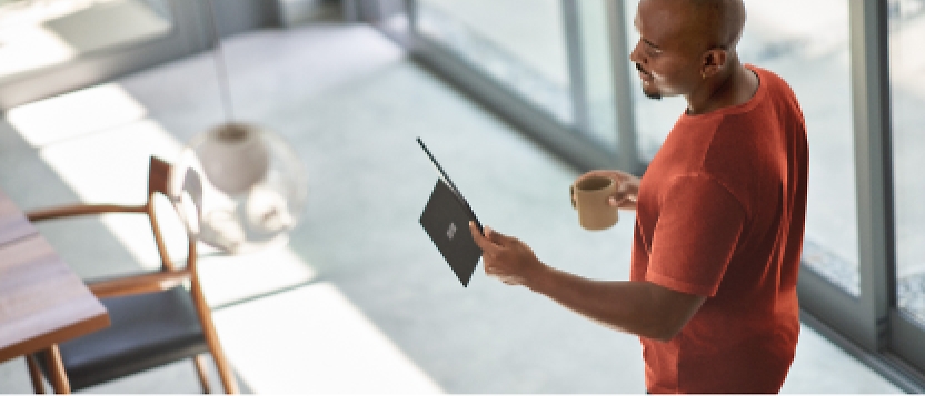 Un homme tient une tablette devant une fenêtre.