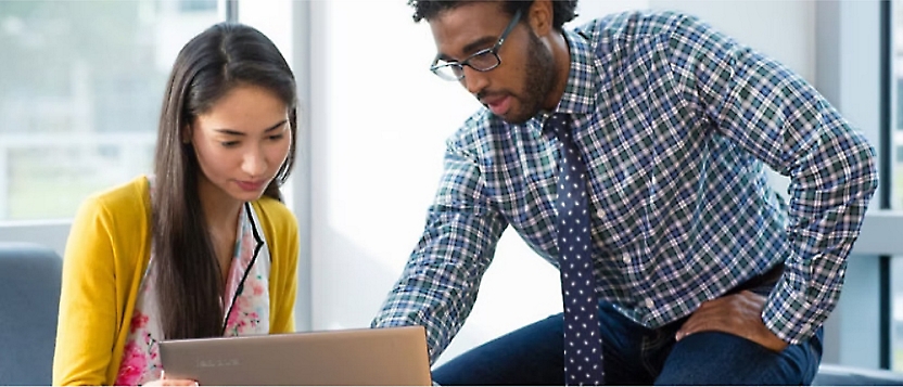 Two people looking into a laptop