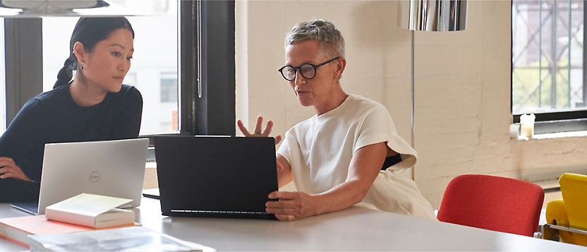 two professionals talking while working on laptop