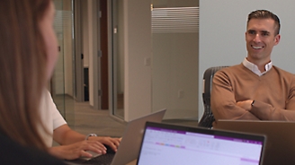 A person sitting in an office with his arms crossed