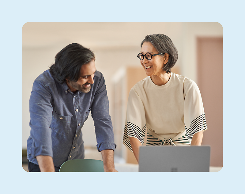 A person and another person looking at a computer and laughing