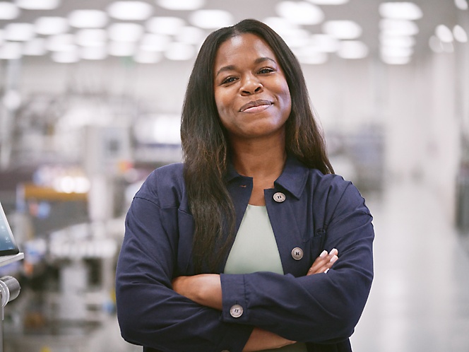 Een foto van een lachende vrouw die een grijs T-shirt en een blauwe jas draagt