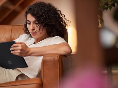 Une femme couchée sur un canapé et utilisant sa tablette