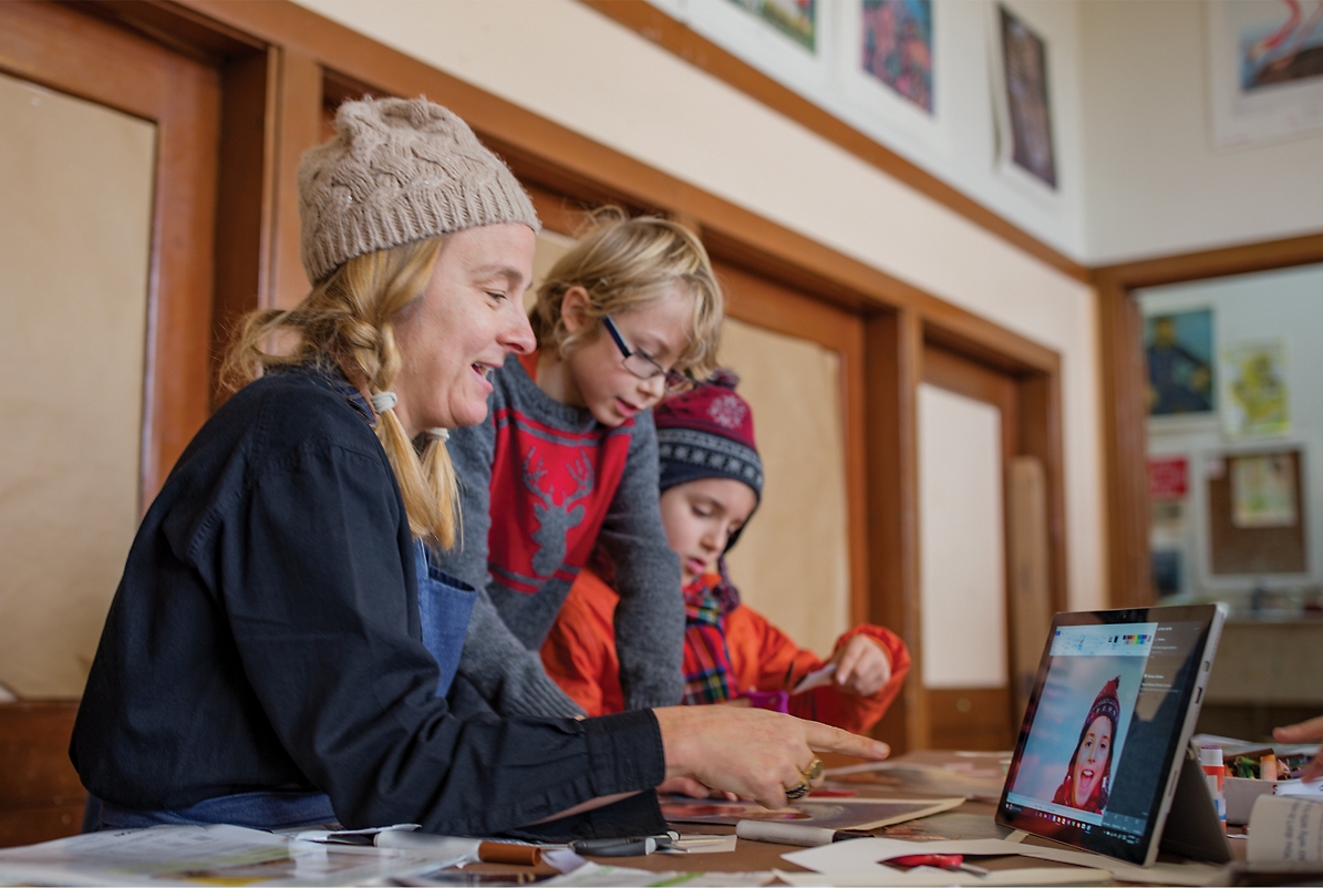 A person and children looking at a computer