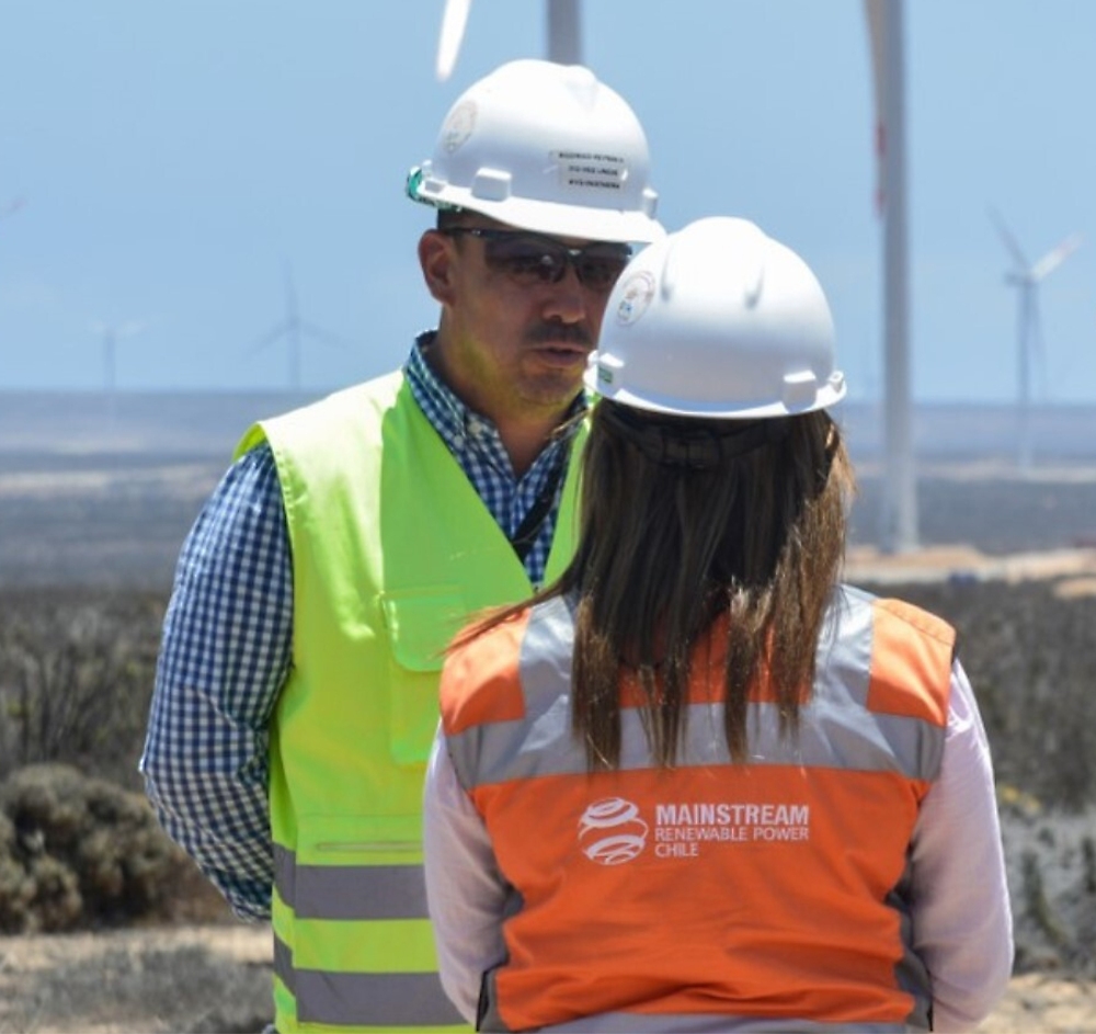 A person and another person wearing hard hats and reflective vests