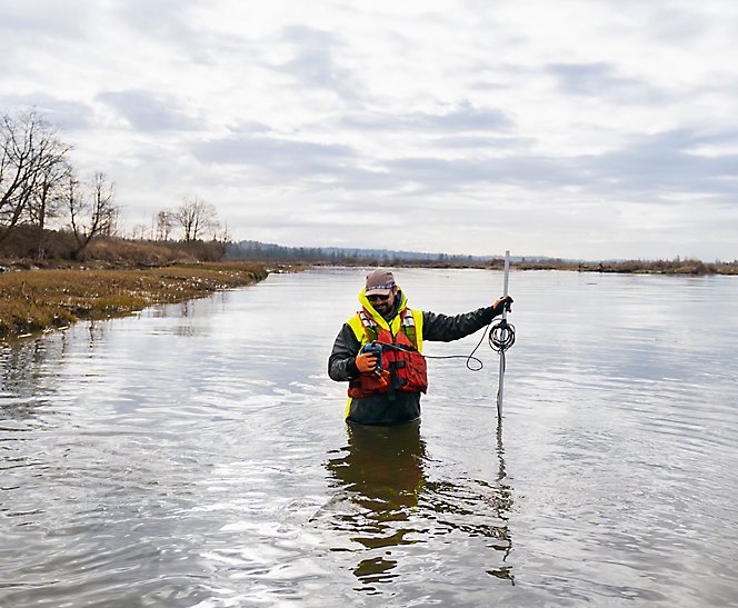 A person in a body of water holding a pole