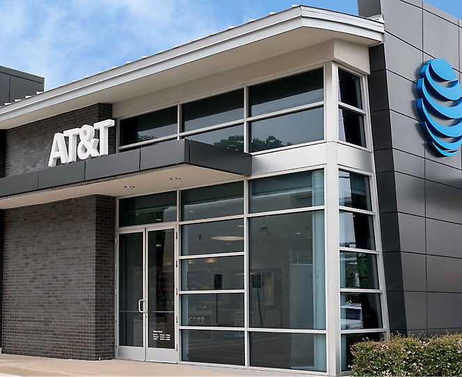 En bygning i grå farge med AT&T skrevet og logoen på toppen av bygningen.