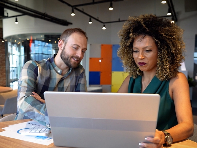 Two people looking at a laptop in an office.