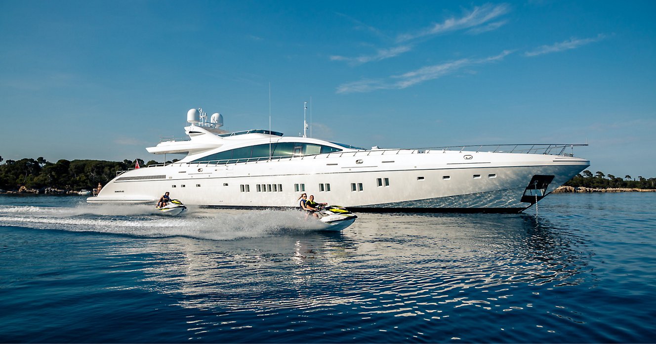 A person is riding a jet ski and a yatch next to it