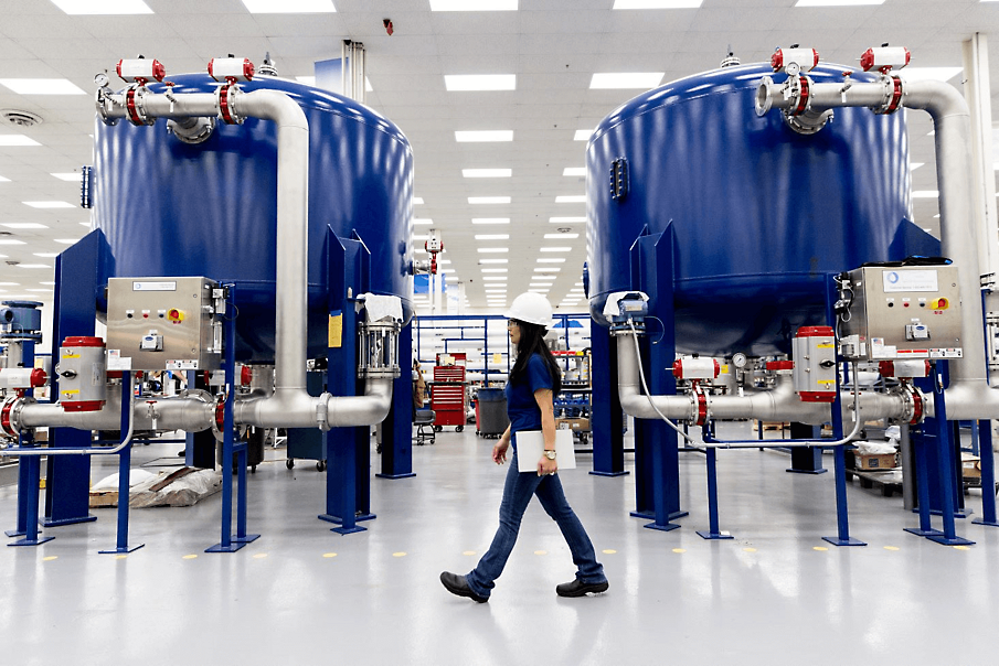 A person wearing a hard hat walking through a factory