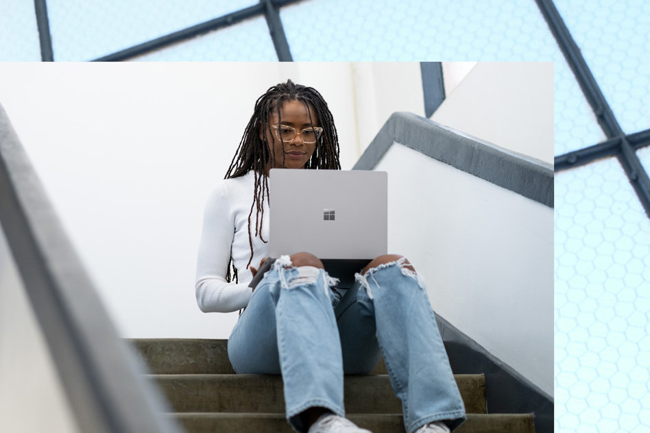 Nainen käyttää platinanväristä Surface Laptop 5 -laitetta porraskäytävässä.