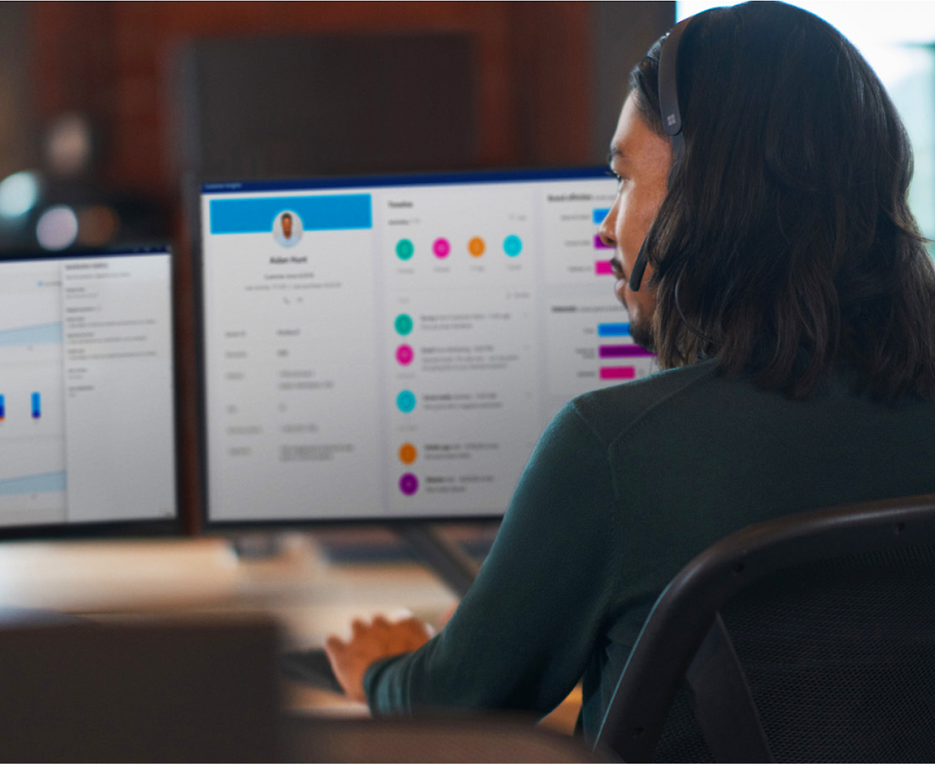 A man is sitting at a desk with two monitors in front of him.