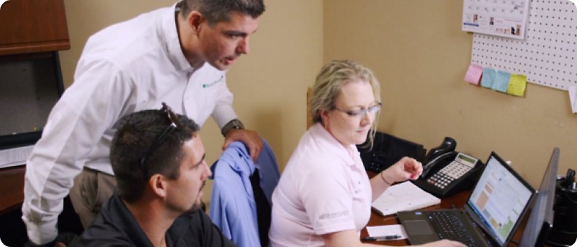 A group of people in an office looking at a laptop.