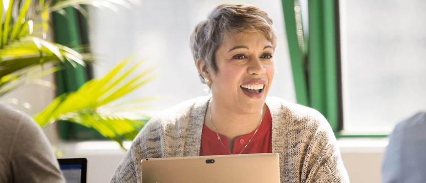 A group of people laughing while using a tablet computer.