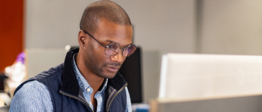 A man in glasses is working on a computer.