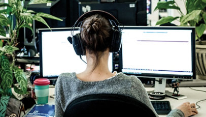 Woman sitting at desk with two monitors.