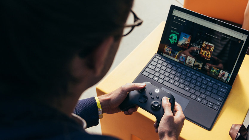 Angled a person using an Xbox controller with a Surface laptop.