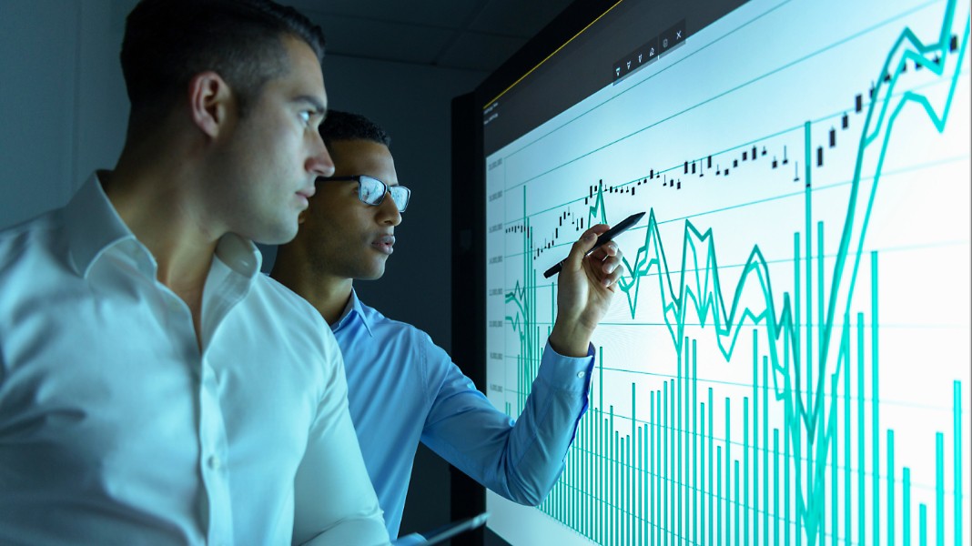 Two people charting data points on a large screen.