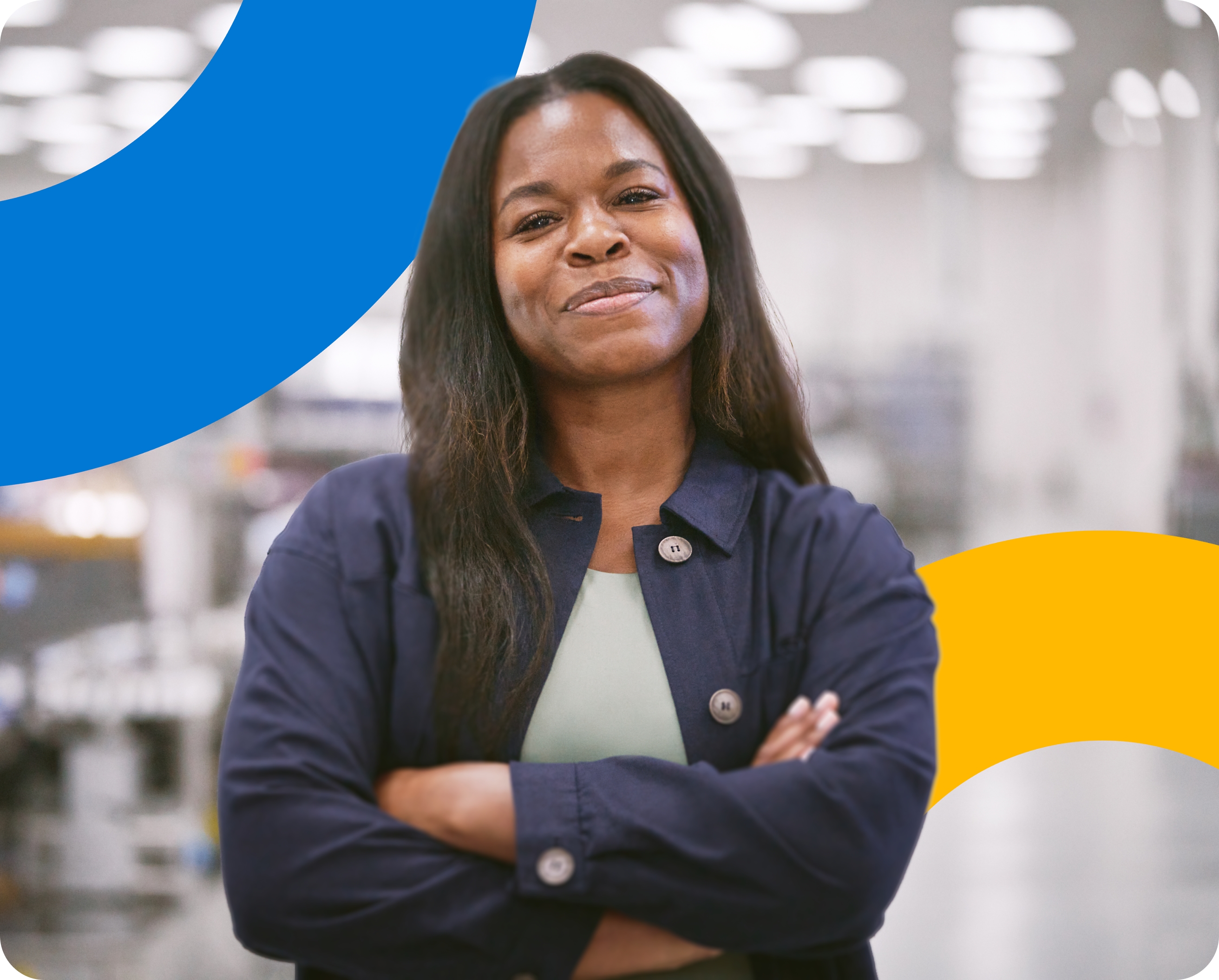 A woman standing in a factory with her arms crossed.