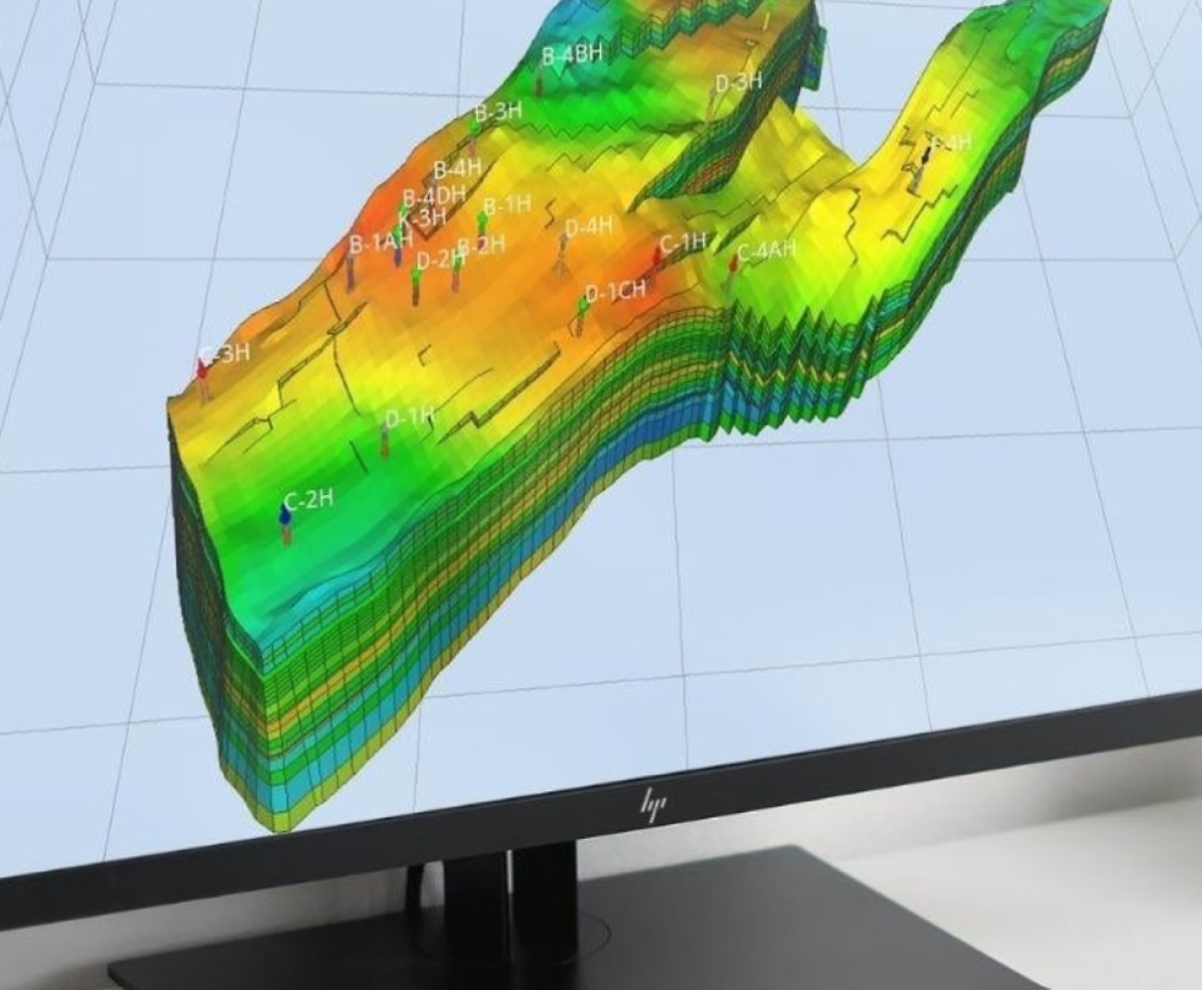 A computer monitor displays a 3D geological map with various color layers and labeled points.