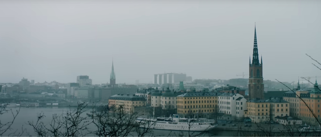 Eine neblige Stadtansicht mit einem Gewässer und mehreren angedockten Booten in der Nähe von bunten Gebäuden und Kirchtürmen im Hintergrund