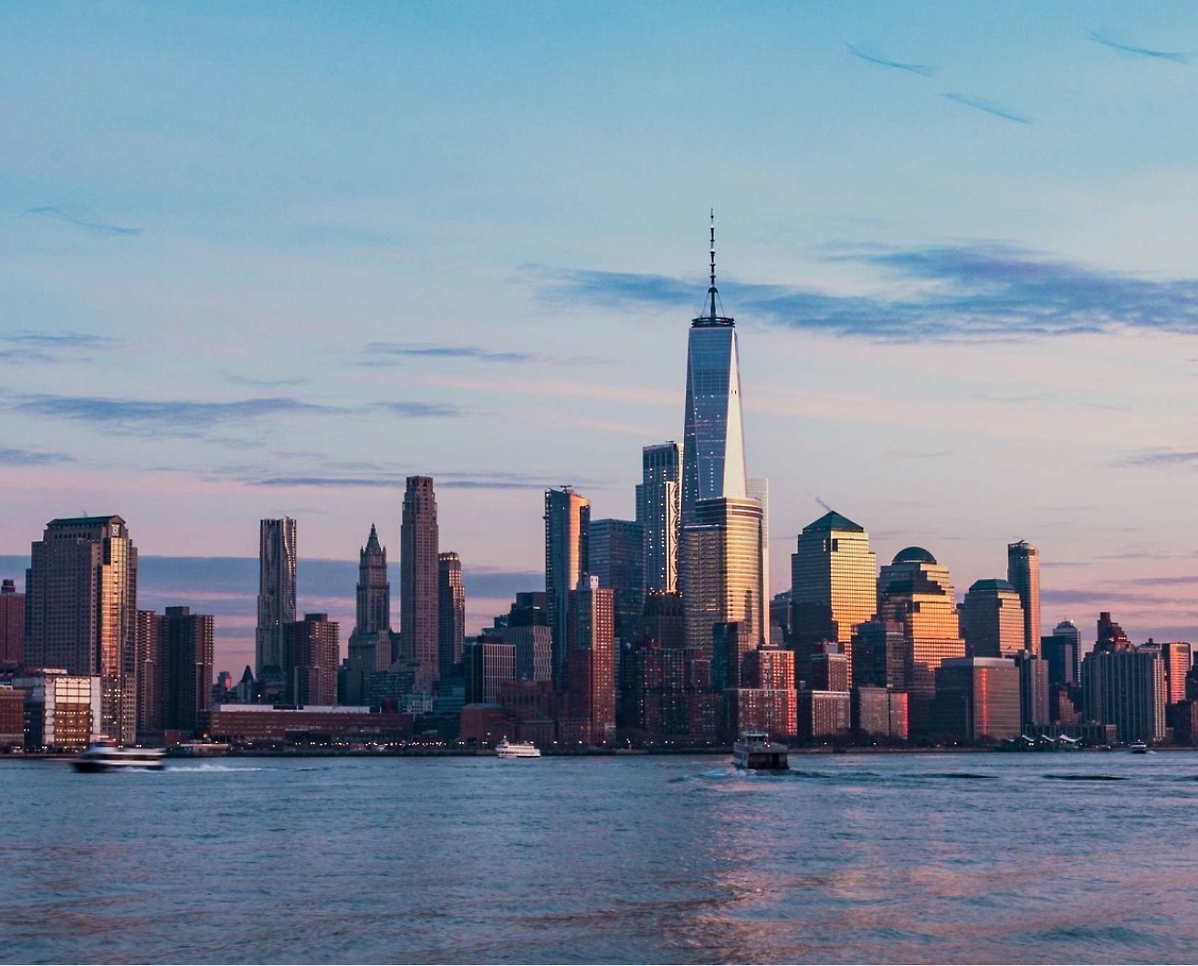 A city skyline at dusk featuring tall buildings with the tallest one in the center