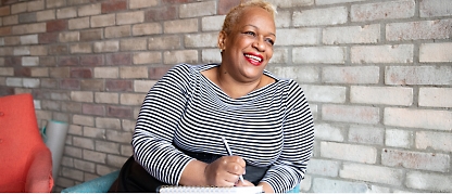 A woman smiling while holding a pen