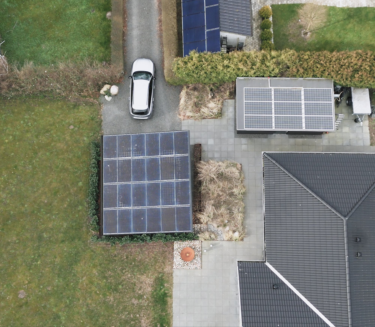 Aerial view of a house with solar panels on the roof, a car parked in the driveway