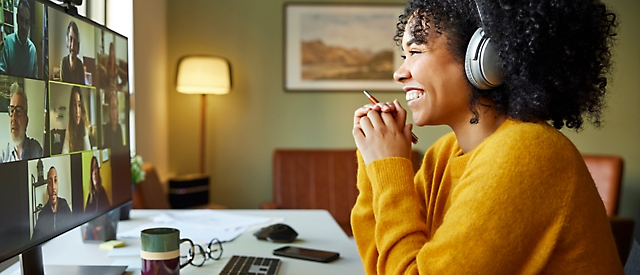 Een vrouw die een hoofdtelefoon draagt en voor een computerscherm zit.