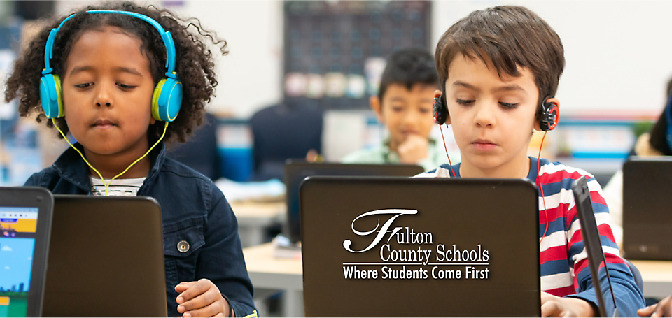 Two children wearing heading with laptops infront of them