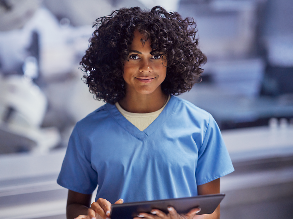 A woman smiling and holding a tablet.