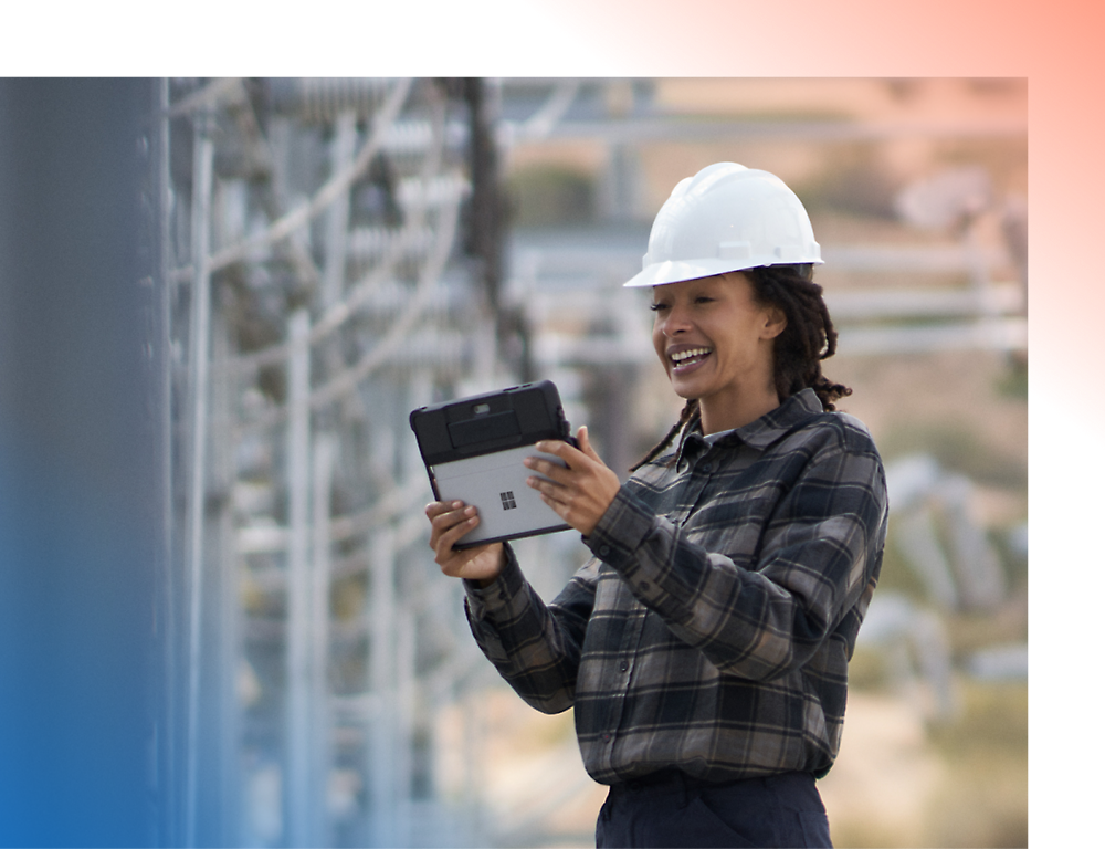 A person wearing a hard hat and holding a tablet