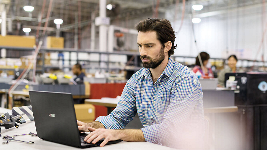 A person working in a warehouse on a laptop.